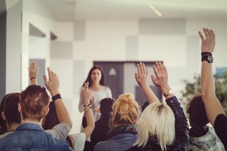 classroom of students raising their hands