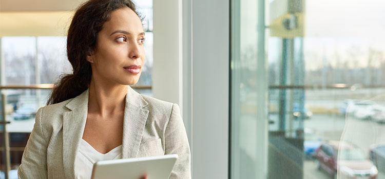 forensic psychologist holding electronic notepad looking out office window