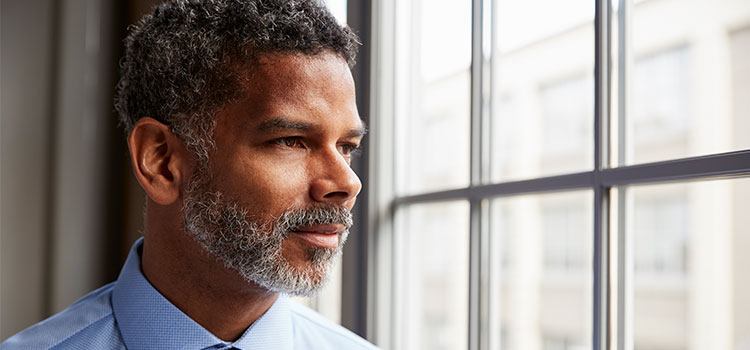 man looking out window contemplatively