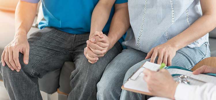 couple hold hands while hearing test results from counselor