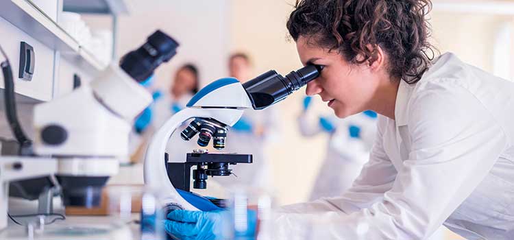 woman genetics counselor looks in microscope