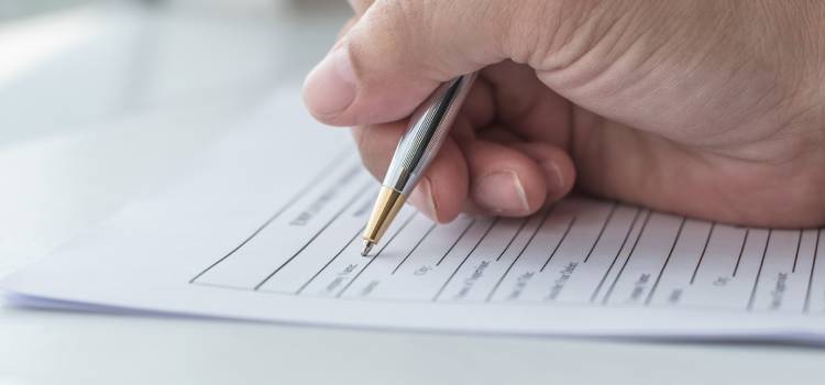right hand filling out a state application for licensure