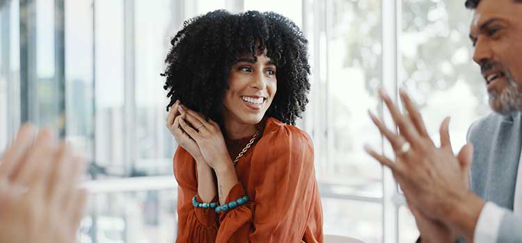 woman smiles at man's speech in life coach group
