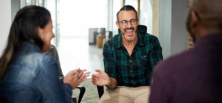 man laughs with two people in group