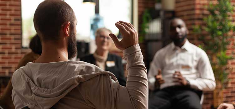 group session with male therapist calling on man with raised hand