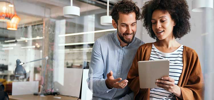 two smiling therapists discuss licensing options on tablet