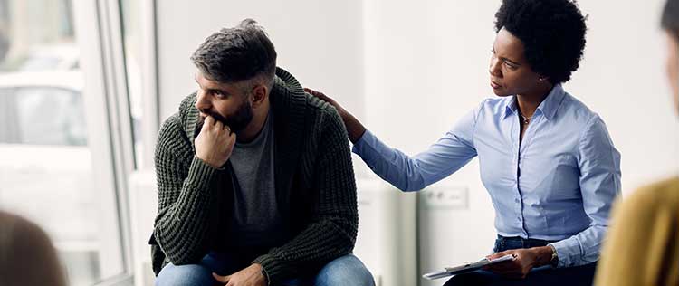 grief counselor pats bereft client on shoulder