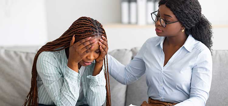 grief cunselor consoles patient with head in hands