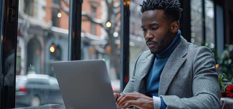 man sits in cafe on snowy day and works on laptop