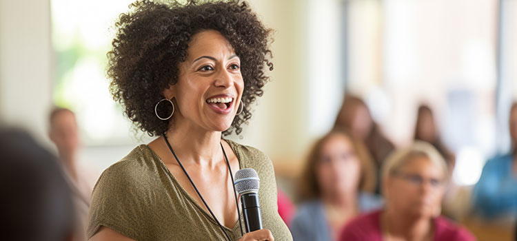 health educator holds microphone and speaks to group at community healthcare session
