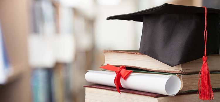 cap and diploma rest on stack of books