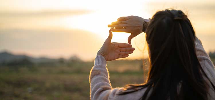 woman holding hand up to create frame looking toward the future