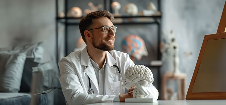research psychologist sits at desk with model of human brain