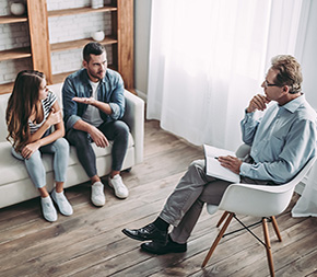 couple in conflict sit in sparsely decorated marriage and family therapist office