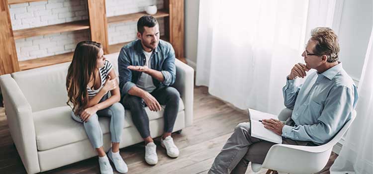 couple in conflict sit in sparsely decorated marriage and family therapist office