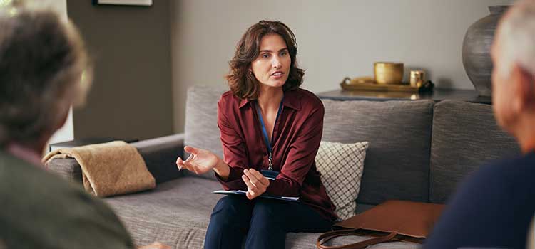 a social worker sits on a couch and speaks with her clients